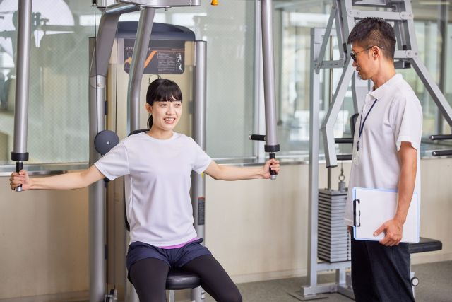 トレーナーと筋トレをしている女性