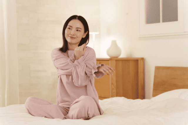 ベッドでストレッチする女性