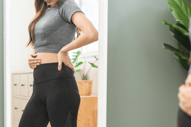 鏡の前で体型を気にする女性